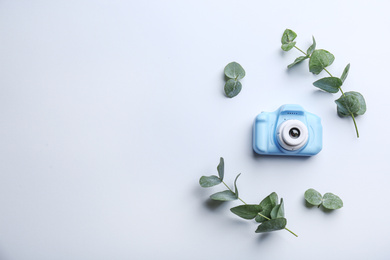 Photo of Toy camera and eucalyptus on white background, top view. Space for text