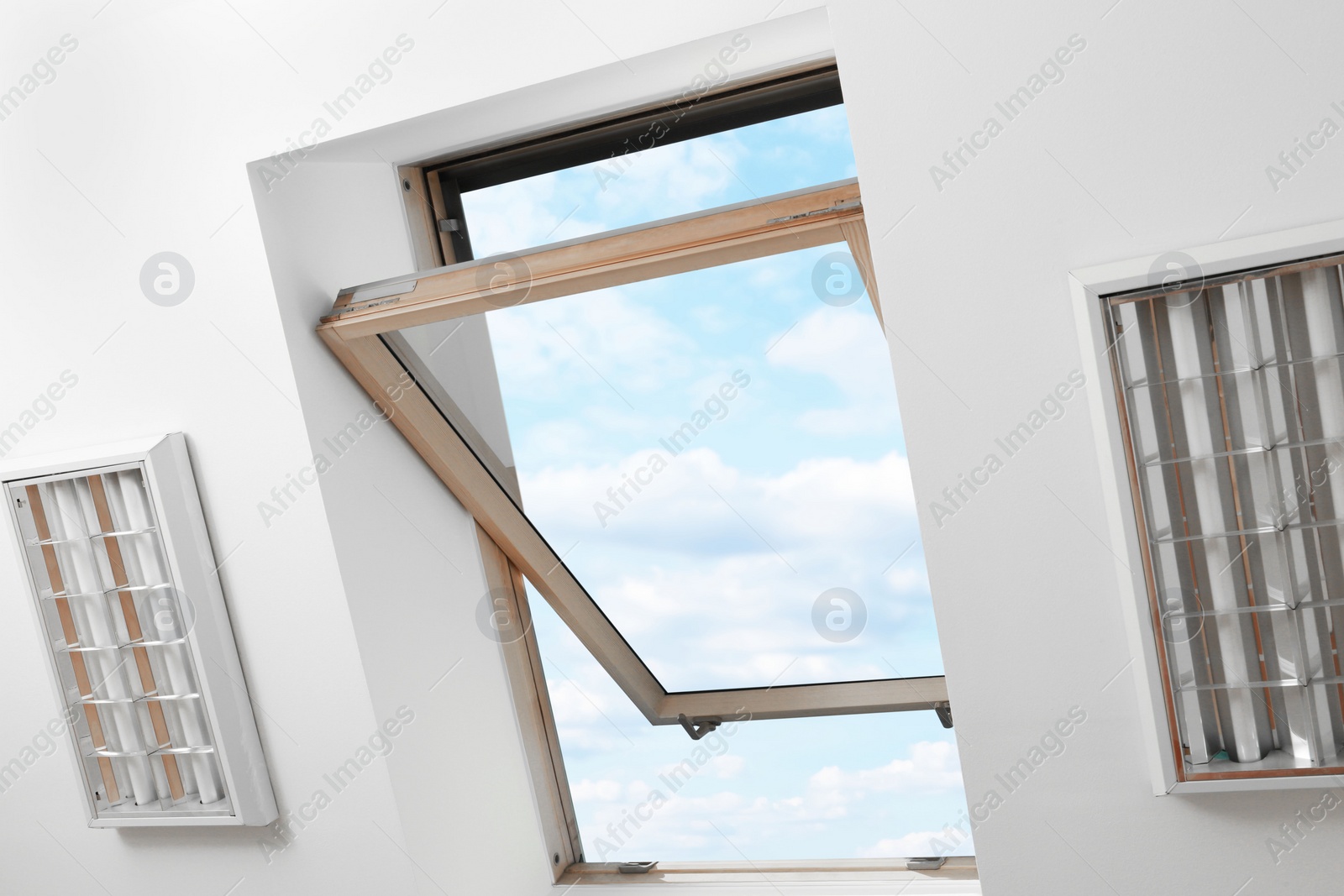 Photo of Open skylight roof window on slanted ceiling in attic room, bottom view