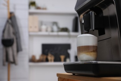 Modern coffee machine with cup of latte in office kitchen, space for text
