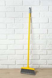 Photo of Plastic broom near white brick wall indoors