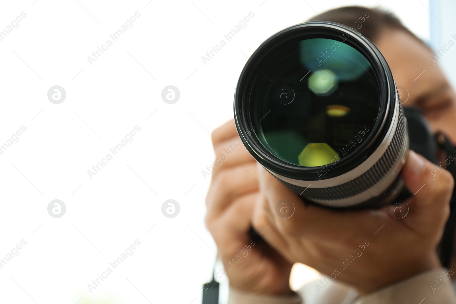 Photo of Male photographer with professional camera on white background. Space for text