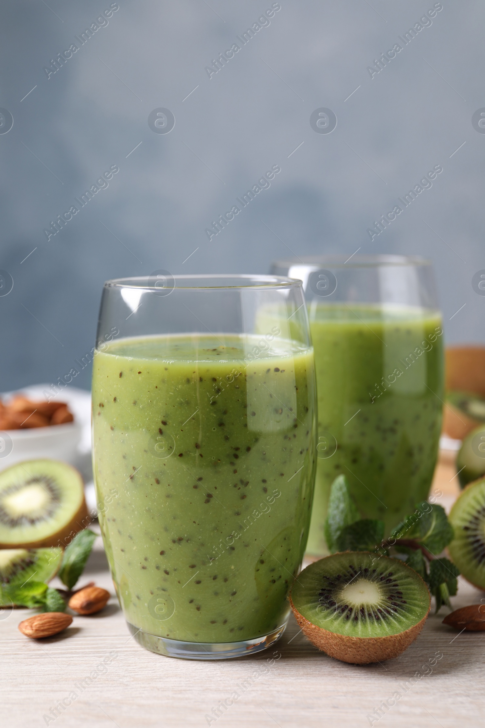 Photo of Delicious kiwi smoothie and ingredients on white wooden table