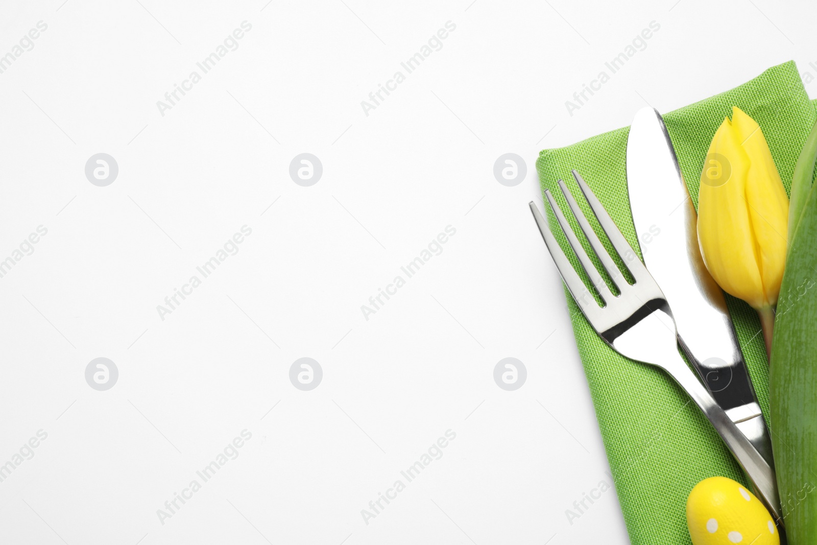 Photo of Top view of cutlery set with floral decor for Easter celebration on white background