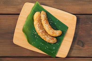 Board with delicious fried bananas on wooden table, top view