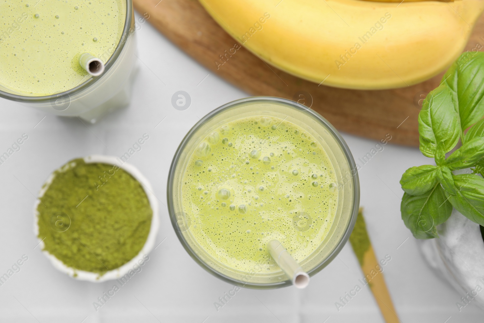 Photo of Glasses of tasty matcha smoothie on white table, flat lay