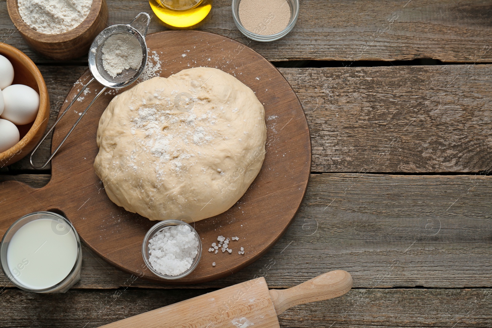 Photo of Fresh yeast dough and ingredients on wooden table, flat lay. Space for text
