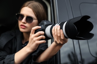 Private detective with camera spying from car, focus on lens