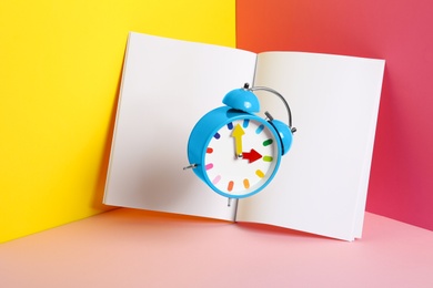 Alarm clock and empty book pages on color background. Mockup for design