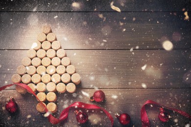 Christmas tree made of wine corks, red ribbon and baubles on wooden table, flat lay. Space for text