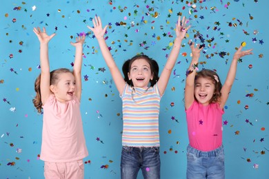 Photo of Adorable little children and falling confetti on light blue background