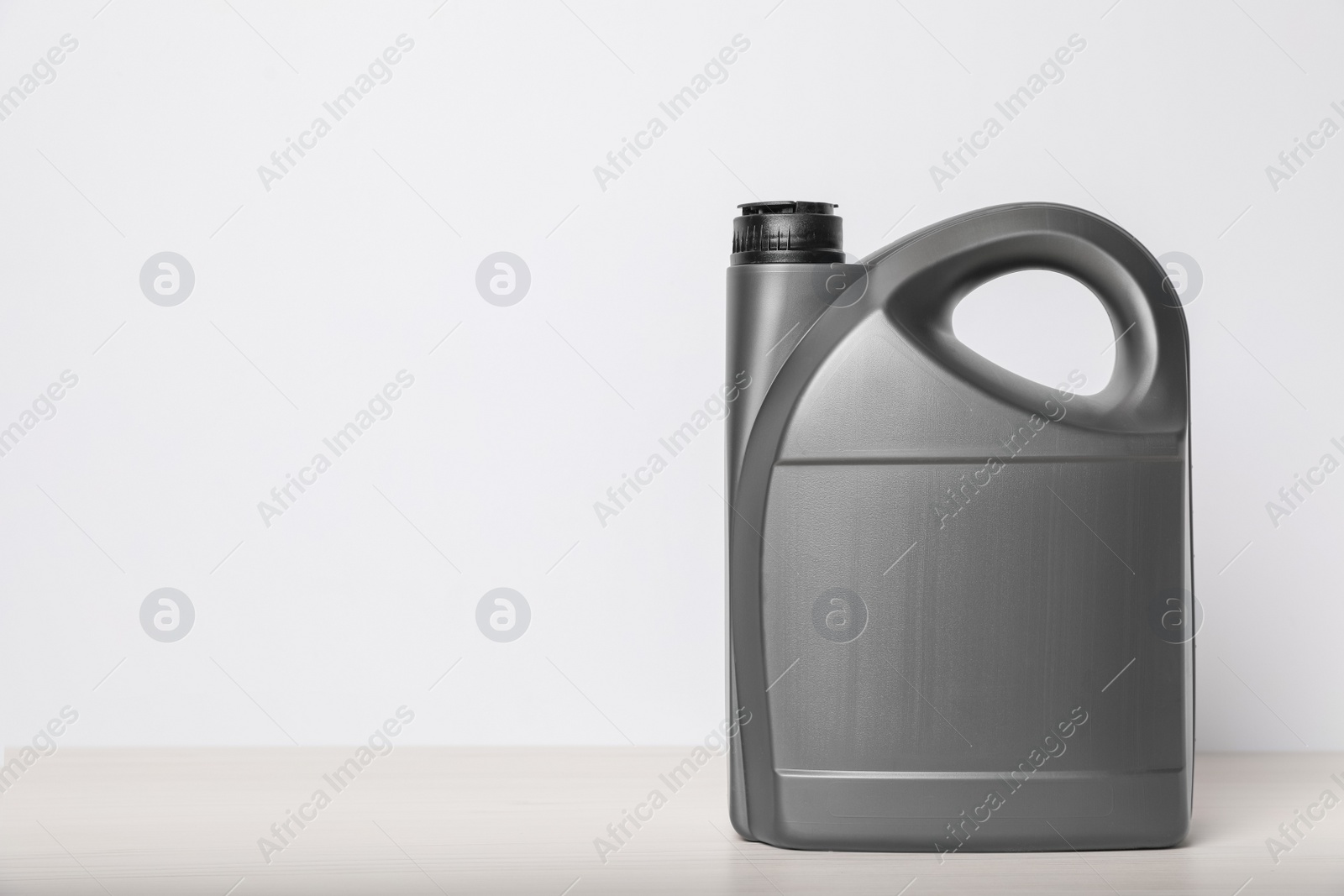 Photo of Motor oil in grey canister on table against white background, space for text