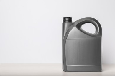 Photo of Motor oil in grey canister on table against white background, space for text