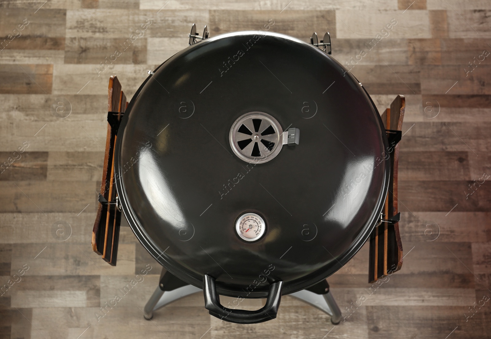 Photo of New modern barbecue grill on wooden floor