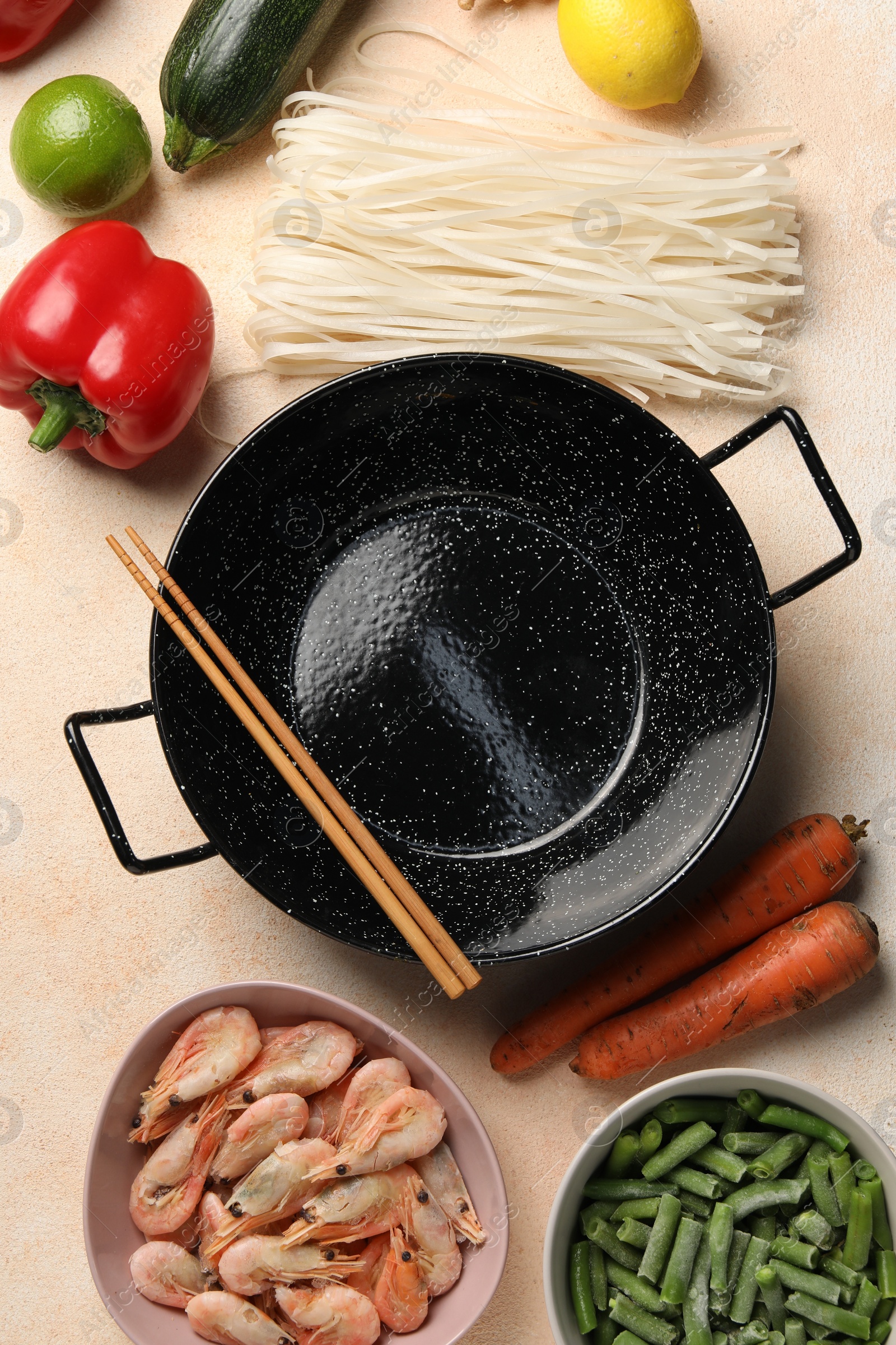 Photo of Black wok, chopsticks and products on color table, flat lay