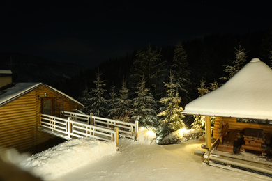 Photo of Modern cottage and wooden gazebo near snowy forest at evening