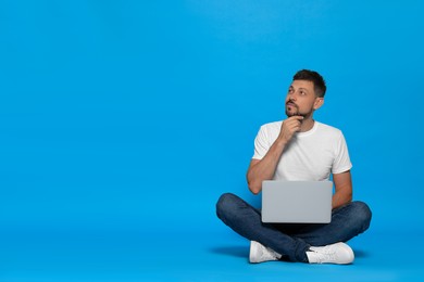 Photo of Pensive man sitting with laptop on light blue background. Space for text
