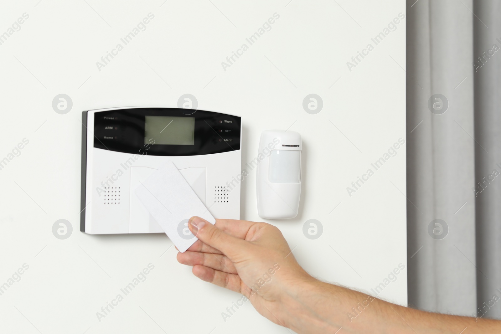 Photo of Home security system. Man using key card indoors, closeup