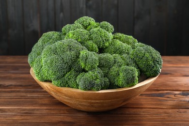 Bowl of fresh raw broccoli on wooden table