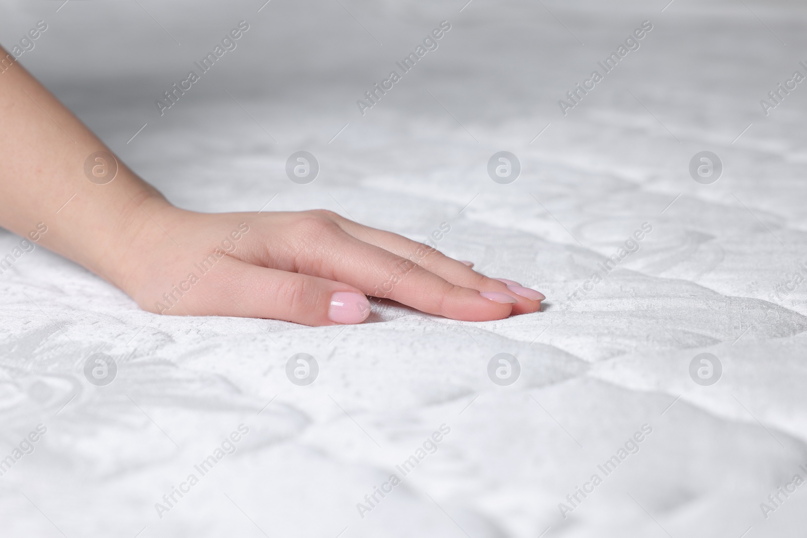 Photo of Woman touching soft white mattress, closeup view