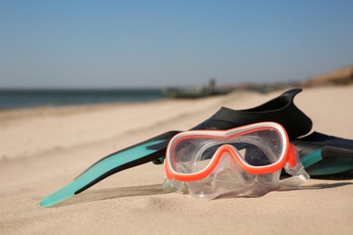 Pair of flippers and diving mask on sandy beach