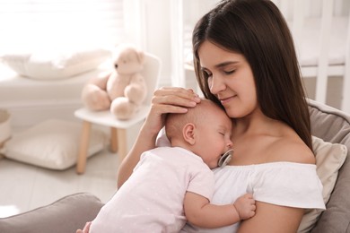 Photo of Happy young mother with her sleeping baby in armchair at home