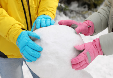 Photo of People making snowman outdoors, closeup. Winter vacation
