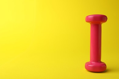 Photo of Stylish dumbbell on yellow background, space for text