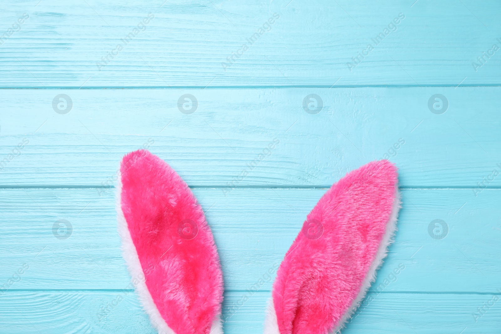 Photo of Decorative bunny ears and space for text on light blue wooden background, flat lay. Easter holiday