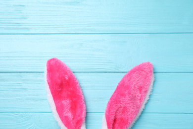 Photo of Decorative bunny ears and space for text on light blue wooden background, flat lay. Easter holiday