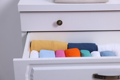 Photo of Open drawer with rolled shirts indoors. Organizing clothes