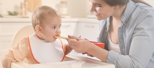 Mother feeding her cute little baby in kitchen. Banner design