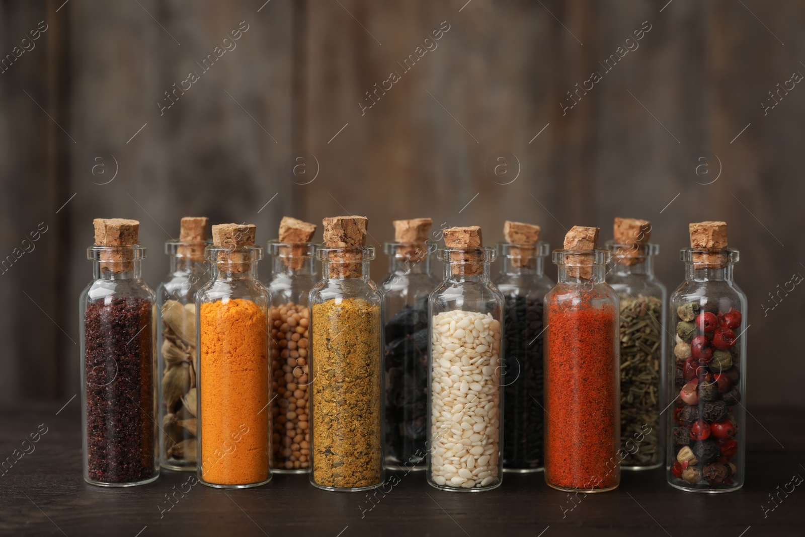 Photo of Bottles with different spices on table against blurred background