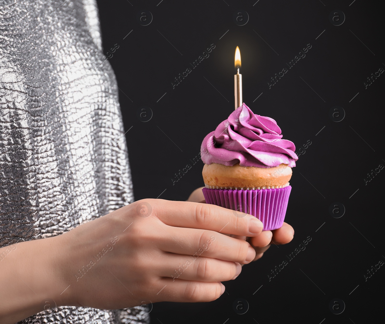 Photo of Woman holding birthday cupcake on black background