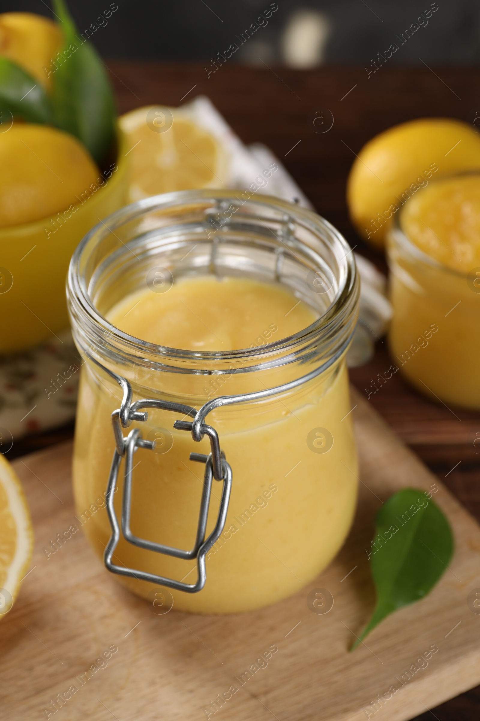 Photo of Delicious lemon curd in glass jar and fresh citrus fruit on table
