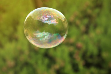 Photo of One beautiful clear soap bubble floating outdoors