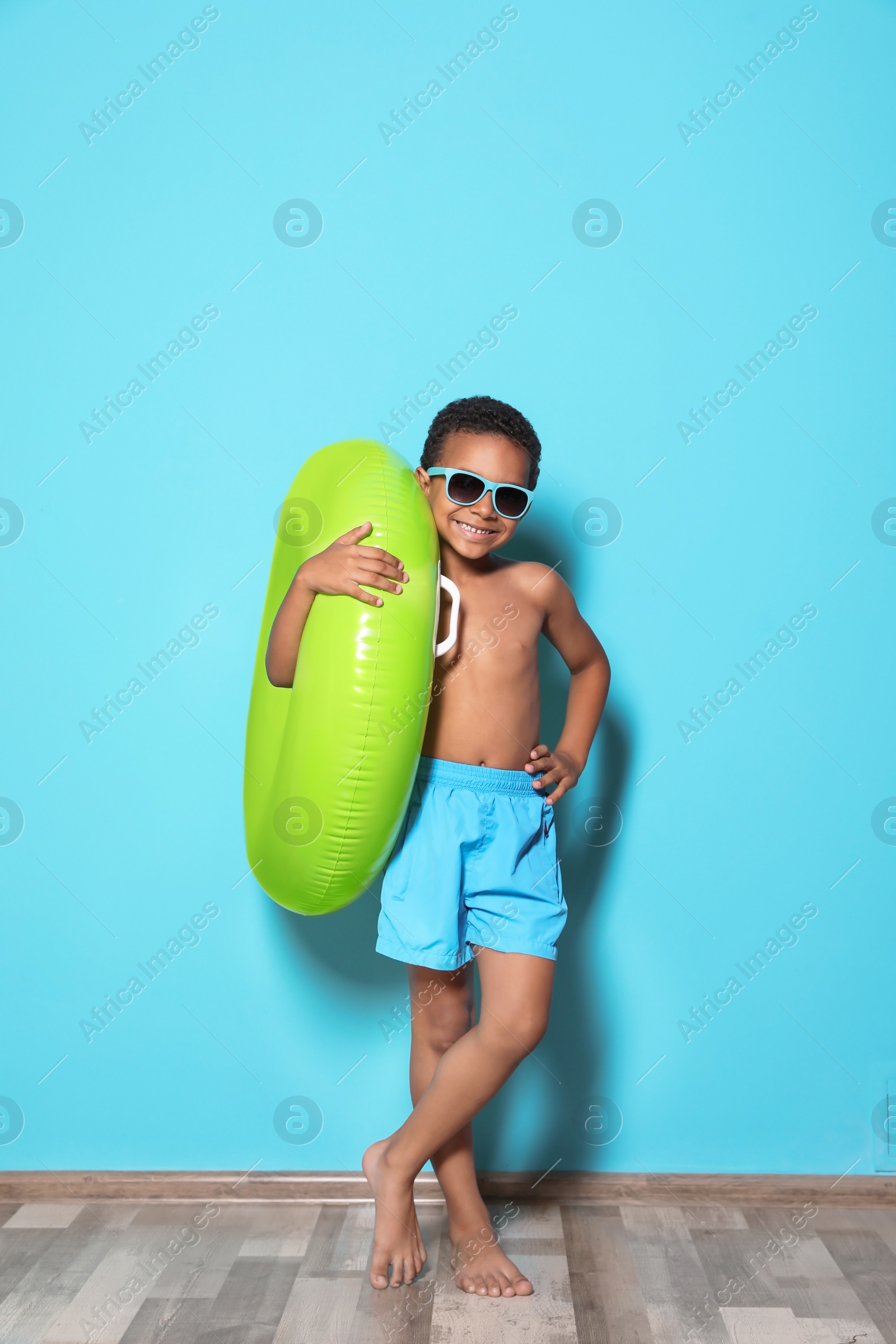 Photo of Cute African American boy with bright inflatable ring near color wall