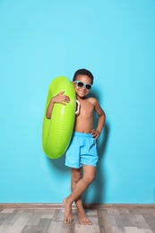 Photo of Cute African American boy with bright inflatable ring near color wall