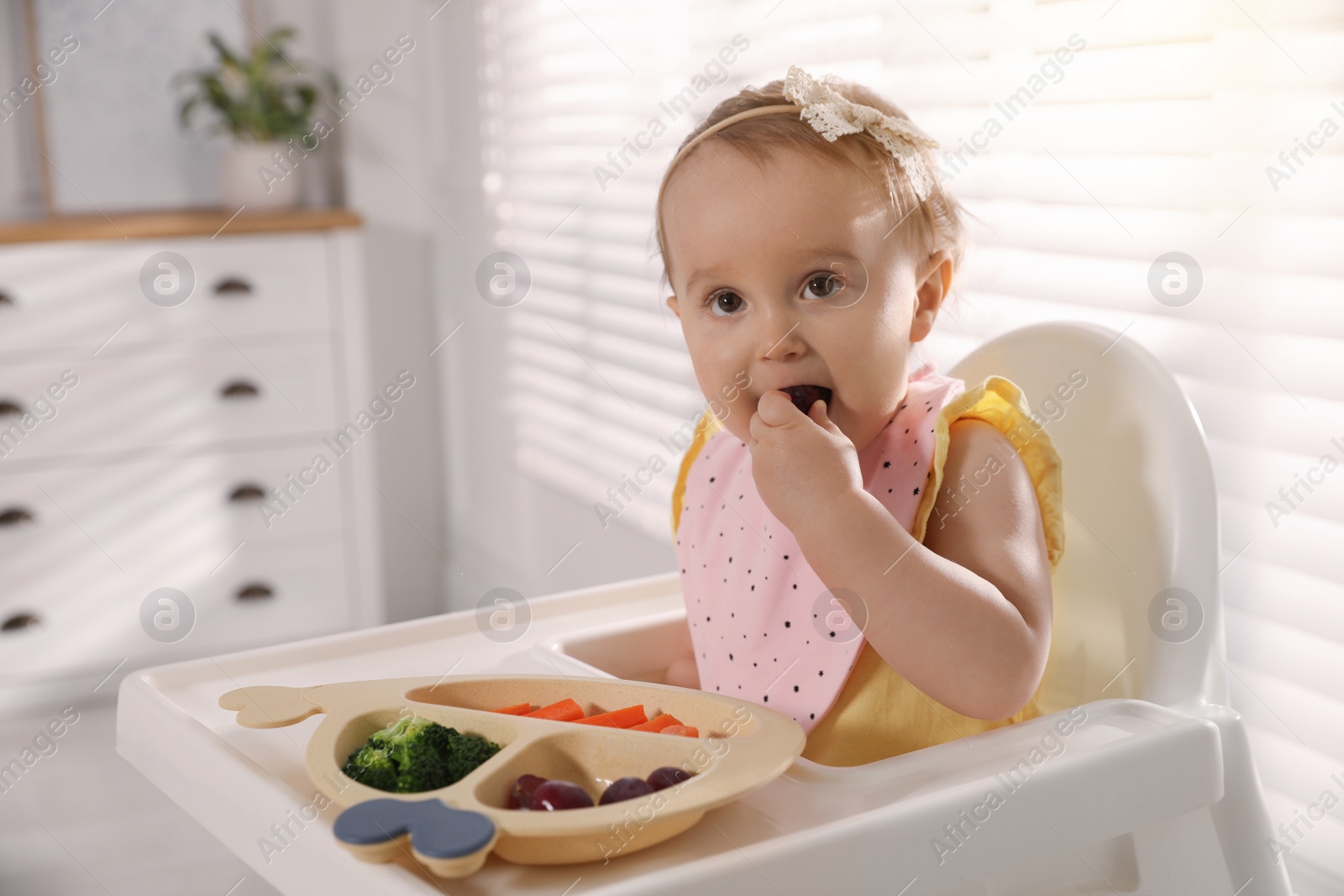 Photo of Cute little baby wearing bib while eating at home