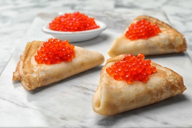 Photo of Thin pancakes with delicious red caviar on table