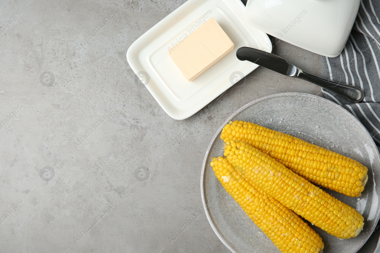 Photo of Flat lay composition with boiled corn cobs on light grey table. Space for text