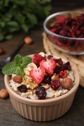 Oatmeal with freeze dried fruits, nuts and mint on wooden table