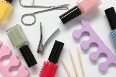 Photo of Nail polishes and set of pedicure tools on white background, flat lay