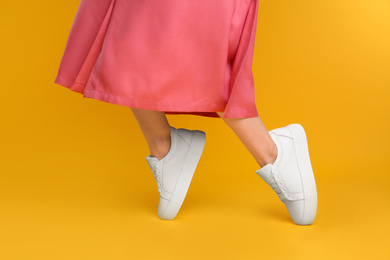 Woman wearing stylish shoes on yellow background, closeup