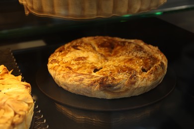 Photo of Delicious pie with tasty filling on counter in bakery shop, closeup