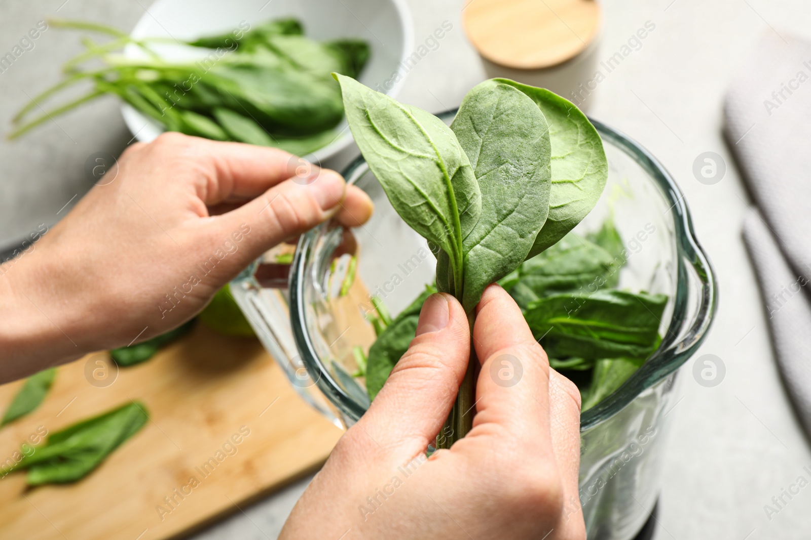 Photo of Woman with fresh green healthy spinach at grey table, closeup