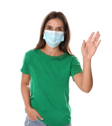 Photo of Woman in protective mask showing hello gesture on white background. Keeping social distance during coronavirus pandemic