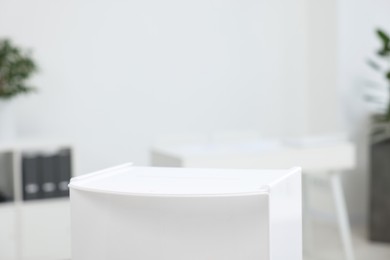 Photo of White ballot box on blurred background, closeup. Space for text