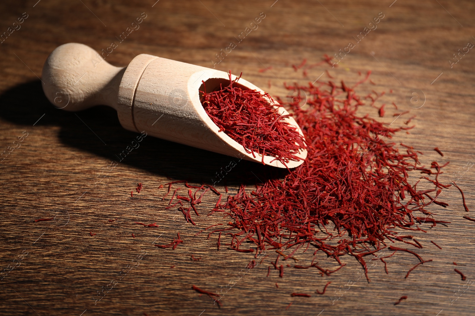 Photo of Aromatic saffron and scoop on wooden table