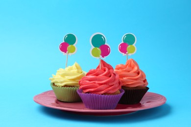 Photo of Delicious cupcakes with bright cream and toppers on light blue background