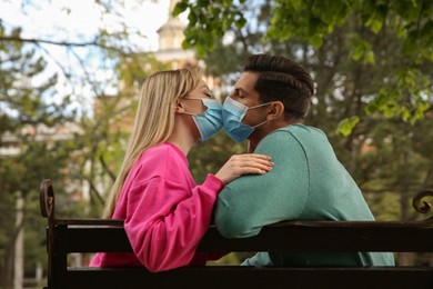 Couple in medical masks trying to kiss outdoors